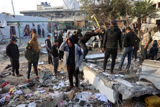 A man uses a hammer as people check the destruction in the aftermath of an Israeli strike at the  Al-Farabi school in the centre of Gaza City, which is sheltering a number of displaced people, on January 15, 2025, amid the ongoing war between Israel and the militant group Hamas. (Photo by Omar AL-QATTAA / AFP)