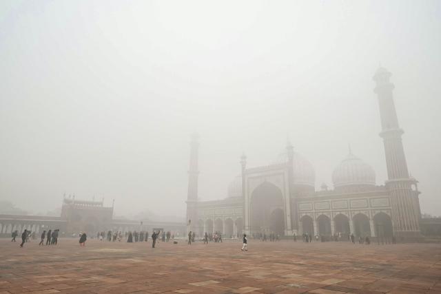 People visit the Jama Masjid (mosque) amid dense fog on a cold winter morning in the walled city area of New Delhi on January 15, 2025. (Photo by Arun SANKAR / AFP)