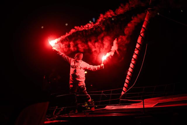 French skipper Yoann Richomme, on his Imoca 60 monohull Paprec Arkea, holds flares as after crossing the line to finish in second place in the 10th edition of the Vendee Globe around the world monohull solo sailing race in Les Sables-d'Olonne, western France, on January 15, 2025. (Photo by Loic VENANCE / AFP)