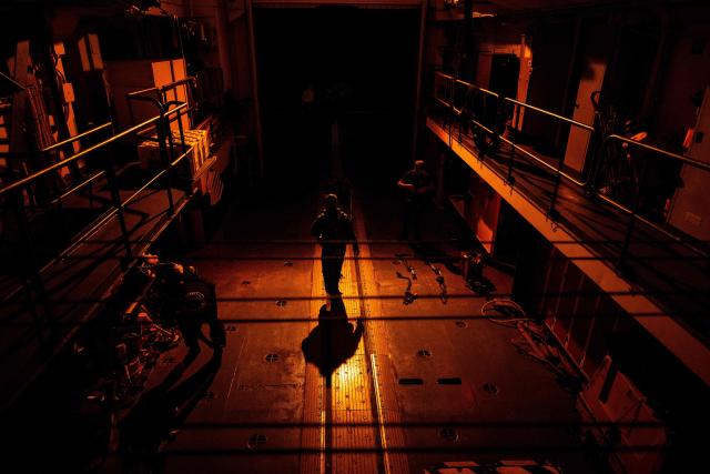 A pilot of the Eurocopter AS565 Panther military helicopter walks in a hangar after landing aboard the French surveillance frigate FS Ventose sailing on a mission off the French Caribbean island of Martinique, on November 13, 2024. The French surveillance frigate FS Ventose is deployed at sea on a Narcops mission to intercept narco-traffickers' vessels potentially transporting narcotics, as part of the fight against drug trafficking in the French West Indies. (Photo by JULIEN DE ROSA / AFP)