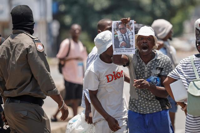 A Mozambique police officer (L) looks on as a protester holds a poster of Mozambique opposition leader Venancio Mondlane in Maputo on January 15, 2025, following the inauguration of Daniel Chapo as the President of Mozambique. Mozambique swore in Daniel Chapo as president on January 15, 2025 following months of post-election violence that an NGO says has killed more than 300 people.
Vowing "to devote all my energies to defending, promoting and consolidating national unity", Chapo, 48, extends his Frelimo party's 50-year rule of the gas-rich African nation. Opposition candidate Venancio Mondlane claims that the October 2024 election was rigged. (Photo by PHILL MAGAKOE / AFP)