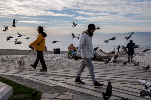 People walk along Alimos beach near Athens on January 15, 2025. (Photo by Angelos TZORTZINIS / AFP)