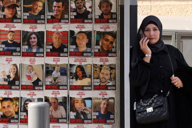 A woman speaks on the phone at a bus stop decorated with portraits of Israelis hostages held in the Gaza Strip since the Oct.7 2023 attack by Hamas militants, in Jerusalem on January 15, 2025, amid the ongoing war between Israel and Hamas. Key mediator Qatar said negotiations for a Gaza truce and hostage release deal were in their "final stages" on January 14, expressing hope an agreement could be reached "very soon". (Photo by HAZEM BADER / AFP)