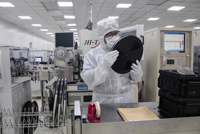 An employee inspect semiconductor chips at a factory in Binzhou, in eastern China's Shandong province on January 15, 2025. (Photo by AFP) / China OUT