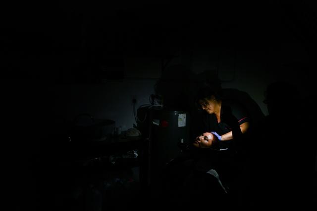 An employee washes a woman's hair during a blackout in Buenos Aires on January 16, 2025. The National Weather Service issued an alert for "extreme temperatures" in central and northern Argentina, affecting 17 of the country's 23 provinces, including Buenos Aires, where due to the heat and high demand for electricity, nearly 40,000 homes suffered blackouts. (Photo by LUIS ROBAYO / AFP)