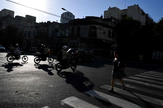 A woman walks on a street during a blackout in Buenos Aires on January 16, 2025. The National Weather Service issued an alert for "extreme temperatures" in central and northern Argentina, affecting 17 of the country's 23 provinces, including Buenos Aires, where due to the heat and high demand for electricity, nearly 40,000 homes suffered blackouts. (Photo by LUIS ROBAYO / AFP)