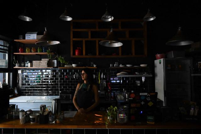 Milagros Oviedo, 27, waits at a kitchen during a blackout in Buenos Aires on January 16, 2025. The National Weather Service issued an alert for "extreme temperatures" in central and northern Argentina, affecting 17 of the country's 23 provinces, including Buenos Aires, where due to the heat and high demand for electricity, nearly 40,000 homes suffered blackouts. (Photo by LUIS ROBAYO / AFP)