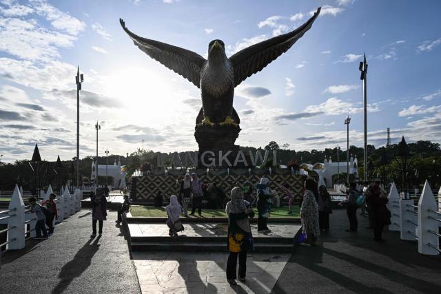 Tourists gather by the eagle statue at Dataran Lang, in Malaysia's resort island of Langkawi on January 18, 2025. (Photo by MOHD RASFAN / AFP)