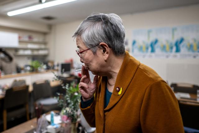 This picture taken on December 14, 2024 shows retired unpaid parole officer "hogoshi" Teruko Nakazawa smoking a cigarette during an interview with AFP in a cafe in Tokyo. Around 47,000 citizen volunteers known as "hogoshi" far outnumber the 1,000 salaried probation officers working in Japan. (Photo by Philip FONG / AFP) / TO GO WITH: Japan-social-crime-prison-volunteer, FEATURE by Tomohiro OSAKI