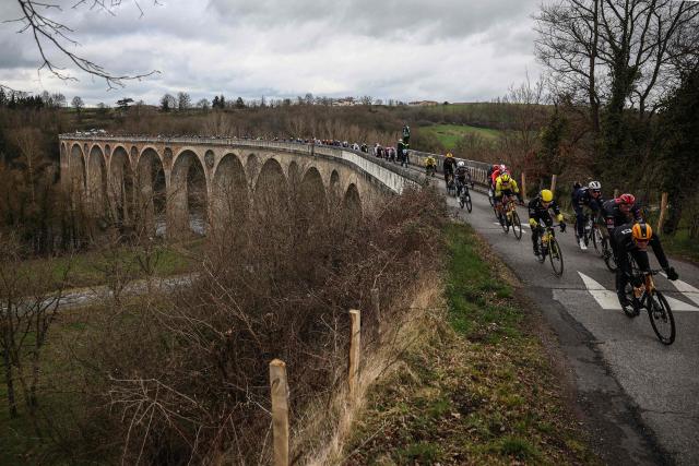 The pack of riders cycles on the Chessieux Viaduct during the 5th stage of the Paris-Nice cycling race, 203,3 km between Saint-Just-en-Chevalet  and La Côte-Saint-André, on March 13, 2025. (Photo by Anne-Christine POUJOULAT / AFP)