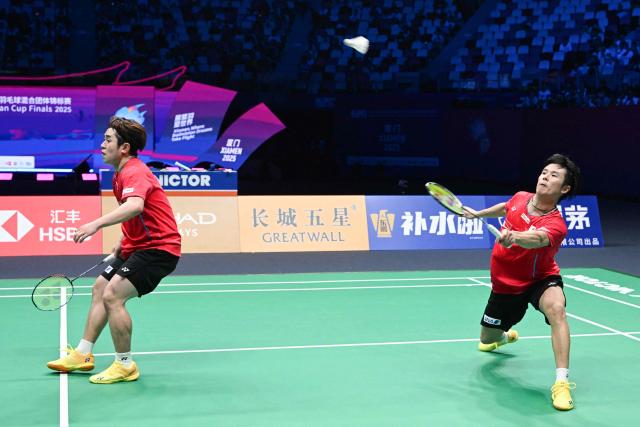 Japan's Takuro Hoki (L) and Yugo Kobayashi hit a return to Malaysia’s Aaron Chia and Soh Wooi Yik in their men’s doubles match at the Sudirman Cup badminton championship in Xiamen, China’s southeastern province on May 1, 2025. (Photo by ADEK BERRY / AFP)