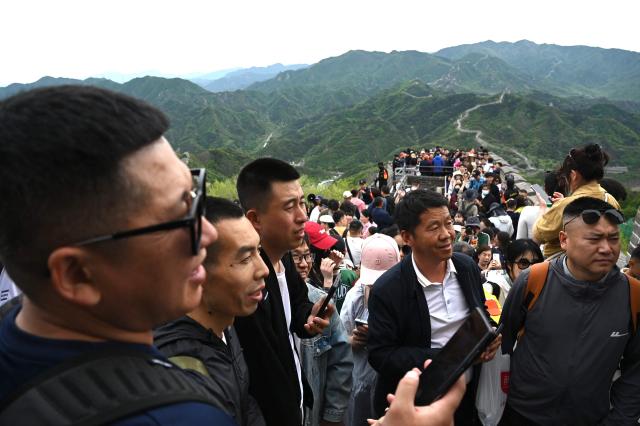A group of men wait to take photos on the Great Wall of China at Badaling, north of Beijing, on May 1, 2025, the first day of a 5-day national May Day holiday. (Photo by GREG BAKER / AFP)