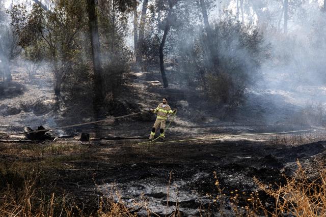 An Israeli firefighter helps to extinguish a fire near Latrun Monastery in central Israel, on May 1, 2025. Israeli firefighting teams battled wildfires near Jerusalem for a second day on May 1, with police reporting the reopening of several major roads that had been closed. (Photo by JOHN WESSELS / AFP)
