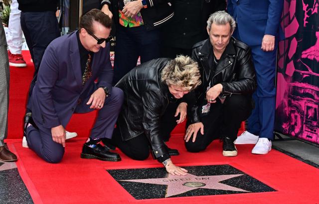 Green Day's Billie Joe Armstrong (C0, flanked by Tre Cool (L) and Mike Dirnt (R) touches the band's their newly unveiled star on the Hollywood Walk of Fame during a ceremony in Hollywood, California, on May 1, 2025. (Photo by Frederic J. BROWN / AFP)