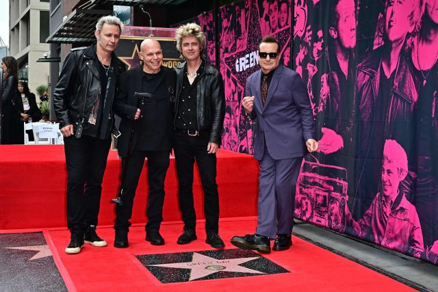 Green Day's Mike Dirnt (L), Billie Joe Armstrong (2R) and Tre Cool (R) pose with US television host Matt Pinfield near their newly unveiled star on the Hollywood Walk of Fame during a ceremony in Hollywood, California, on May 1, 2025. (Photo by Frederic J. BROWN / AFP)