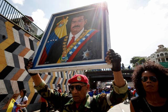 A supporter of the government shows a painting depicting Venezuela's President Nicolas Maduro during a march to commemorate May Day (Labour Day), marking International Workers' Day in Caracas on May 1, 2025. (Photo by Pedro MATTEY / AFP)
