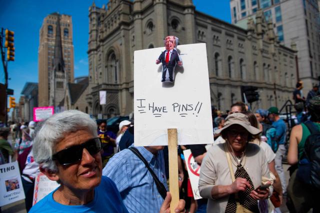 A person holds a sign with a small effigy of US President Donald Trump as they march near Philadelphia City Hall during the “For the Workers, Not the Billionaires May Day Rally” in Philadelphia, Pennsylvania on May 1, 2025. US Senator Bernie Sanders addressed the protesters who marched and participated in an act of civil disobedience. (Photo by Matthew Hatcher / AFP)