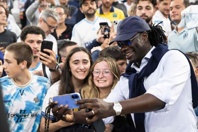 Former French player Bafetimbi Gomis takes a selfie with supporters prior to a Legends football match to celebrate the 125th Anniversary of Olympique de Marseille (OM) football club at the Stade Velodrome in Marseille, southern France, on May 2, 2025.  (Photo by MIGUEL MEDINA / AFP)