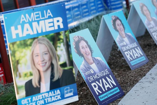 Posters display pictures of Monique Ryan and Amelia Hamer as voters wait to cast their ballots in Australia’s general election at a polling station in Melbourne on May 3, 2025. (Photo by Martin KEEP / AFP)