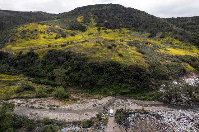 This aerial view shows members of the collective for the search of missing persons and authorities work at the Las Carretas Canyon area in Tijuana, Baja California state, Mexico on May 2, 2025. (Photo by Guillermo Arias / AFP)