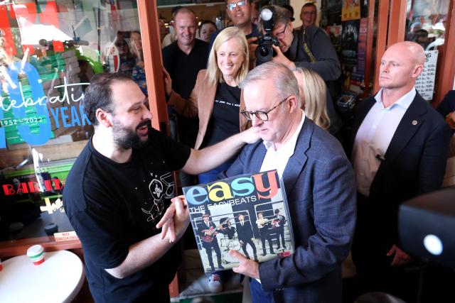 Australia's re-elected Prime Minister Anthony Albanese receives an album as he leaves after a visit to a cafe in Sydney on May 4, 2025, following his party’s decisive federal election victory. (Photo by DAVID GRAY / AFP)