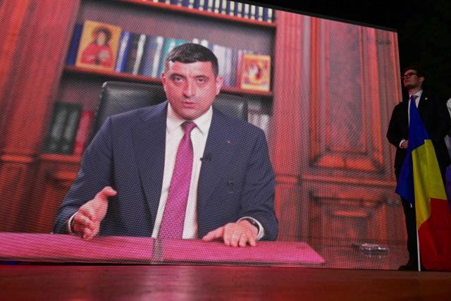 A supporter of the leader of nationalist sovereign party 'Alliance for the Union of Romanians' AUR George Simion stands next to a giant screen on which his video message was transmitted after exit poll results were announced during the first round of the presidential election in Bucharest on May 4, 2025. Romania's far-right candidate George Simion was leading in Sunday's first round of presidential elections according to exit polls, in the rerun of last year's annulled ballot that plunged the European Union member into political turmoil.  
Simion, leader of the nationalist AUR party, scored between 30 to 33 percent of the vote, ahead of two pro-European candidates who took between 21 and 23 percent, according to two polls. (Photo by Daniel MIHAILESCU / AFP) / ALTERNATIVE CROP