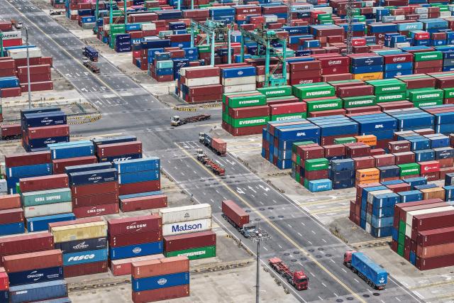 Trucks transport containers at a port in Shanghai on May 9, 2025. China said on May 9 sales to the United States slumped last month while its total exports topped forecasts, as Beijing fought a gruelling trade war with its superpower rival. (Photo by AFP) / China OUT