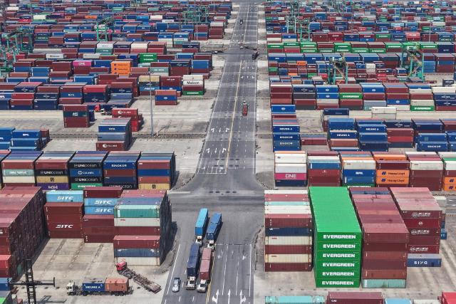Trucks transport containers at a port in Shanghai on May 9, 2025. China said on May 9 sales to the United States slumped last month while its total exports topped forecasts, as Beijing fought a gruelling trade war with its superpower rival. (Photo by AFP) / China OUT