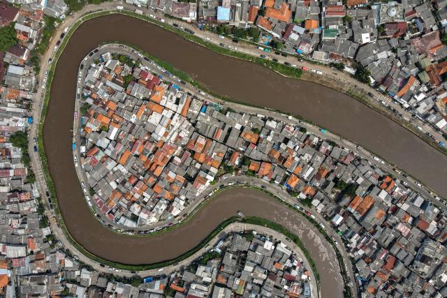 TOPSHOT - This aerial picture shows a river running through a residential area in Jakarta on May 9, 2025. (Photo by BAY ISMOYO / AFP)
