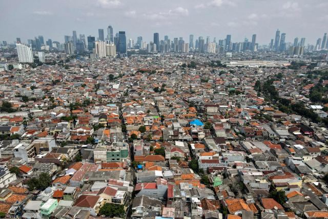 This aerial picture shows housing before the skyline of the Jakarta business district on May 9, 2025. (Photo by BAY ISMOYO / AFP)