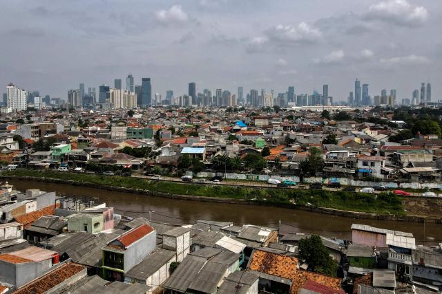 This aerial picture shows housing before the skyline of the Jakarta business district on May 9, 2025. (Photo by BAY ISMOYO / AFP)