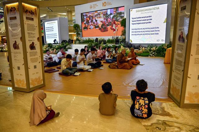 Devotees pray next to a statue of Buddha at a shopping mall in Surabaya on May 9, 2025, ahead of 'Vesak' festival, also known as Buddha Jayanti to commemorate the birth, enlightenment and death of Buddha. (Photo by Juni KRISWANTO / AFP)