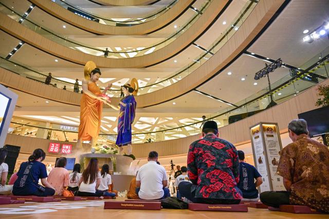Devotees pray next to a statue of Buddha at a shopping mall in Surabaya on May 9, 2025, ahead of 'Vesak' festival, also known as Buddha Jayanti to commemorate the birth, enlightenment and death of Buddha. (Photo by Juni KRISWANTO / AFP)