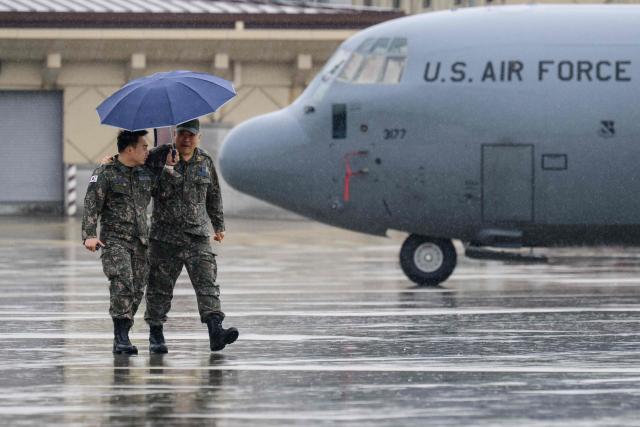 South Korean soldiers walk past a US C-130 Hercules military transport aircraft as it rains during a media day for the Osan Air Power Days 2025 at Osan Air Base in Pyeongtaek on May 9, 2025. (Photo by ANTHONY WALLACE / AFP)