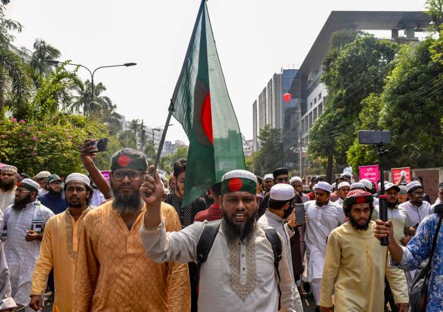 Protesters carrying a national flag shout slogans as they gather near the State Guest House Jamuna, the official residence of Bangladesh's Chief Advisor Office of Interim Government Muhammad Yunus, demanding a ban on the ousted Sheikh Hasina’s party, the Awami League, in Dhaka on May 9, 2025. (Photo by Munir UZ ZAMAN / AFP)