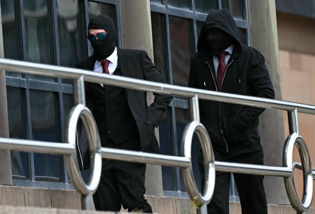 (FILES) Daniel Graham (L), and Adam Carruthers, wearing face-coverings, arrive at Newcastle Magistrates' Court in Newcastle-Upon-Tyne, north east England on May 15, 2024, where they face two counts of criminal damage following the felling of the Sycamore Gap tree, in September 2023. Two men were on Friday, May 9, found guilty of the "deliberate and mindless" felling of one of the UK's most iconic trees in a case that sparked national outrage. (Photo by Paul ELLIS / AFP)