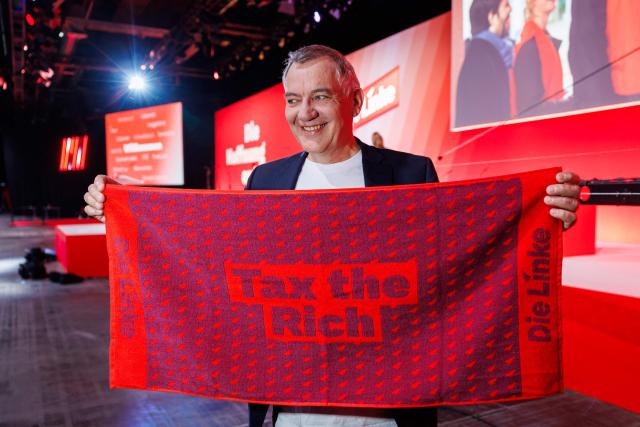 Jan van Aken, co-leader of Germany's The Left (Die Linke) party is pictured with "Tax the Rich" merchandise prior to the start of the federal party congress in Chemnitz, eastern Germany on May 9, 2025. (Photo by JENS SCHLUETER / AFP)