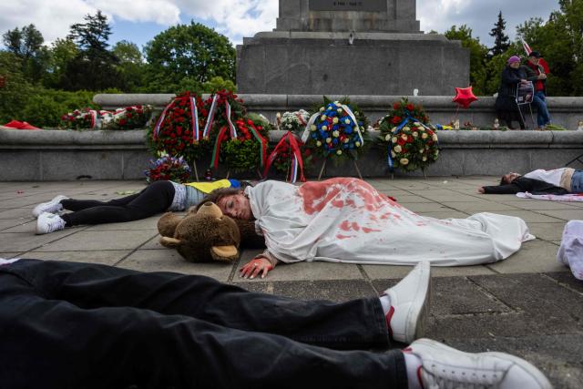 Ukrainian activists lie on the pavement, simulating the bodies of victims, to protest the full-scale Russian invasion of Ukraine, at the mausoleum of Soviet soldiers in Warsaw, Poland, on May 9, 2025. (Photo by Wojtek RADWANSKI / AFP)