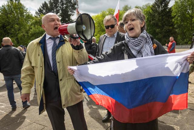A woman with the Russian national flag reacts at the mausoleum of Soviet soldiers in Warsaw, Poland, on May 9, 2025. (Photo by Wojtek RADWANSKI / AFP)