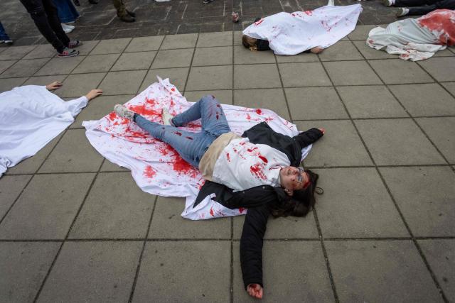 Ukrainian activists lie on the pavement, simulating the bodies of victims, to protest the full-scale Russian invasion of Ukraine, at the mausoleum of Soviet soldiers in Warsaw, Poland, on May 9, 2025. (Photo by Wojtek RADWANSKI / AFP)