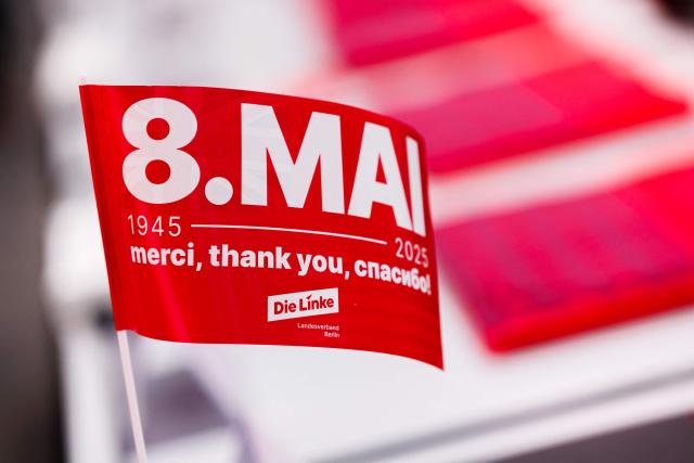 Tables are decorated with merchandise and a small flag reading "May 8th, 1945-2025, Thank you", during the federal party congress of Germany's The Left (Die Linke) party in Chemnitz, eastern Germany, on May 9, 2025. (Photo by JENS SCHLUETER / AFP)