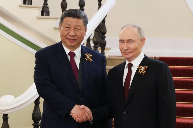 In this pool photograph distributed by the Russian state agency Sputnik, Russia's President Vladimir Putin greets Chinese President Xi Jinping prior to the Victory Day military parade in Moscow on May 9, 2025. Russia celebrates the 80th anniversary of the Soviet Union's victory over Nazi Germany in World War Two (WWII). (Photo by Mikhail METZEL / POOL / AFP)