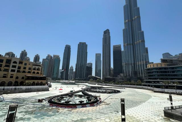 Tall buildings stand behind the Dubai Fountain, emptied for maintenance, in Dubai on May 9, 2025. (Photo by Giuseppe CACACE / AFP)