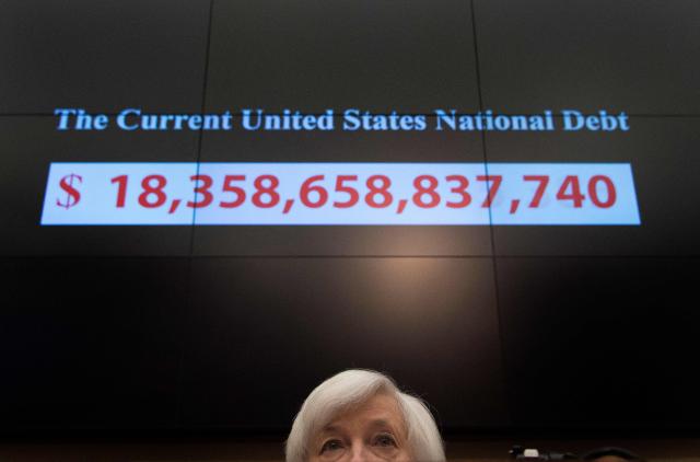 (FILES) A graphic shows the rising current US national debt as Federal Reserve Chair Janet Yellen testifies before the House Financial Services Committee on Capitol Hill in Washington, DC, November 4, 2015. There is a "reasonable probability" the US will hit its borrowing limit in August when Congress is in recess, US Secretary of Treasury Scott Bessent said on May 9, 2025, calling on lawmakers to act. "I respectfully urge Congress to increase or suspend the debt limit by mid-July, before its scheduled break, to protect the full faith and credit of the United States," he wrote in a letter to US Speaker of the House Mike Johnson. (Photo by Jim WATSON / AFP)