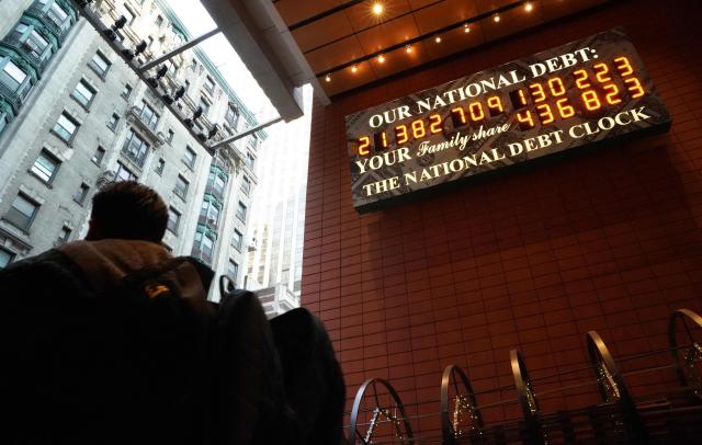 (FILES) A man walks past the he National Debt Clock on 43rd Street in midtown New York City February 15, 2019. There is a "reasonable probability" the US will hit its borrowing limit in August when Congress is in recess, US Secretary of Treasury Scott Bessent said on May 9, 2025, calling on lawmakers to act. "I respectfully urge Congress to increase or suspend the debt limit by mid-July, before its scheduled break, to protect the full faith and credit of the United States," he wrote in a letter to US Speaker of the House Mike Johnson. (Photo by TIMOTHY A. CLARY / AFP)