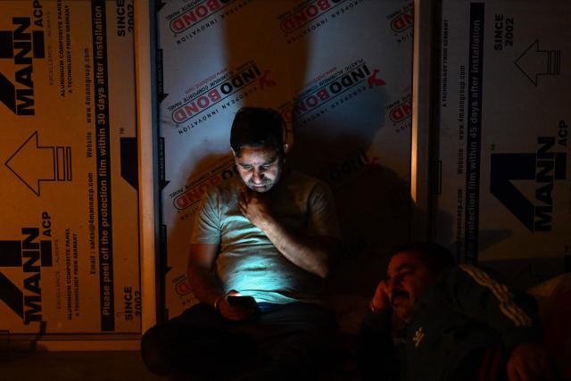 A man checks his mobile phone as he takes shelter in the basement of a building during overnight artillery shelling in the main town of Poonch district on May 9, 2025. The Indian army on May 10 reported fresh Pakistani attacks along the border with its arch-foe as the conflict between the nuclear-armed neighbours spiralled. (Photo by Punit PARANJPE / AFP)