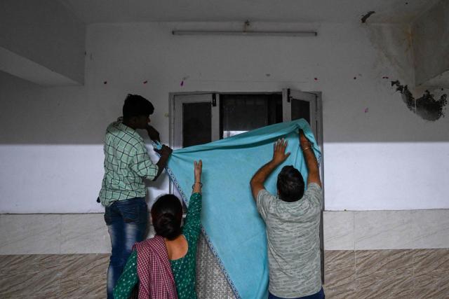 Residents try to cover a window as they take shelter in the basement of a building during overnight artillery shelling in the main town of Poonch district on May 9, 2025. The Indian army on May 10 reported fresh Pakistani attacks along the border with its arch-foe as the conflict between the nuclear-armed neighbours spiralled. (Photo by Punit PARANJPE / AFP)