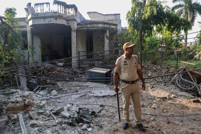 An Indian police personnel stands outside a house that was damaged by Pakistani artillery shelling in Jammu on May 10, 2025. The Indian army on May 10 reported fresh Pakistani attacks along the border with its arch-foe as the conflict between the nuclear-armed neighbours spiralled. (Photo by Rakesh BAKSHI / AFP)
