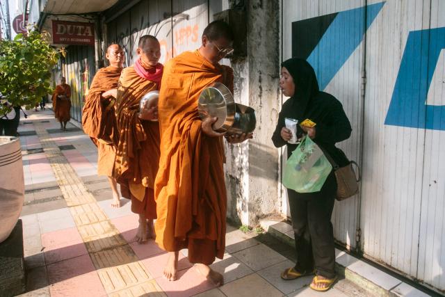 Buddhist monks receive alms along a street in Magelang, Central Java, on May 10, 2025, ahead of Waisak, or Vesak Day. Vesak is the most sacred day for Buddhists, commemorating the birth, enlightenment and death of Siddhartha Gautama, the Buddha, all traditionally believed to have occurred on the full moon day of the Vesakha month in the ancient Indian lunar calendar. (Photo by DEVI RAHMAN / AFP)