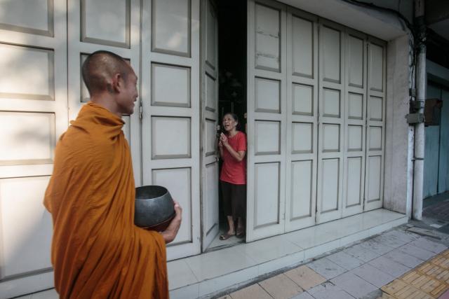 A woman puts her hands together as a Buddhist monk walks by to receive alms in Magelang, Central Java, on May 10, 2025, ahead of Waisak, or Vesak Day. Vesak is the most sacred day for Buddhists, commemorating the birth, enlightenment and death of Siddhartha Gautama, the Buddha, all traditionally believed to have occurred on the full moon day of the Vesakha month in the ancient Indian lunar calendar. (Photo by DEVI RAHMAN / AFP)